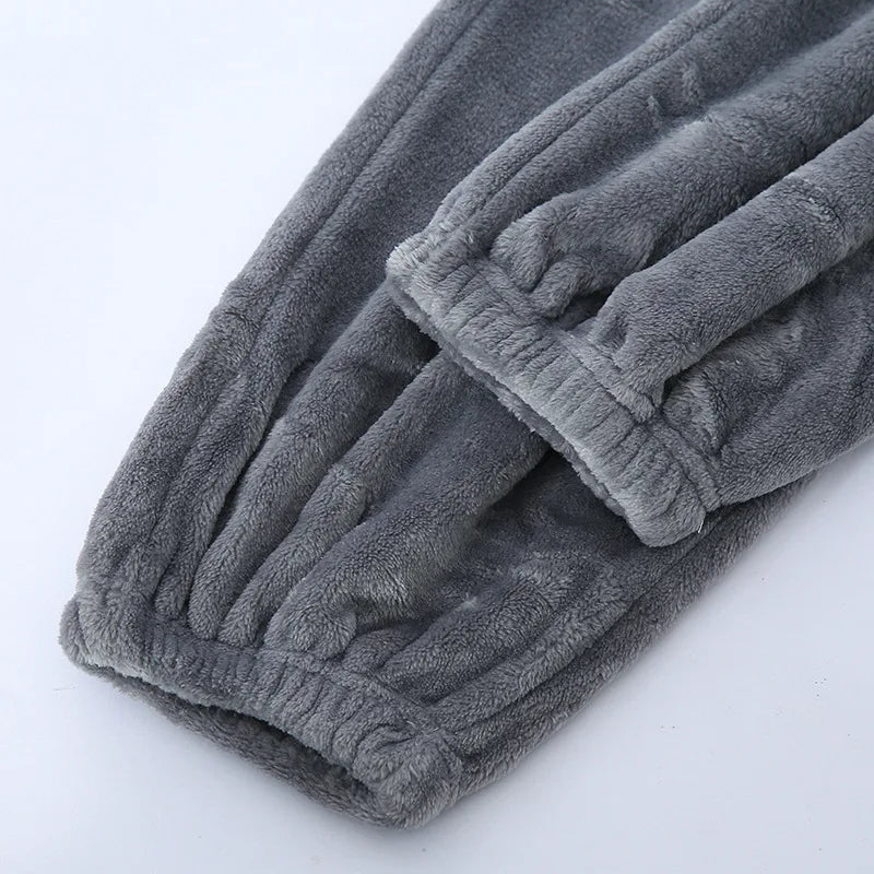 Gros plan sur le bas du pantalon d’un pyjama en flanelle pour homme, en tissu gris épais et ultra doux, avec chevilles élastiquées. Matière chaude, moelleuse et très confortable, idéale pour l’hiver.