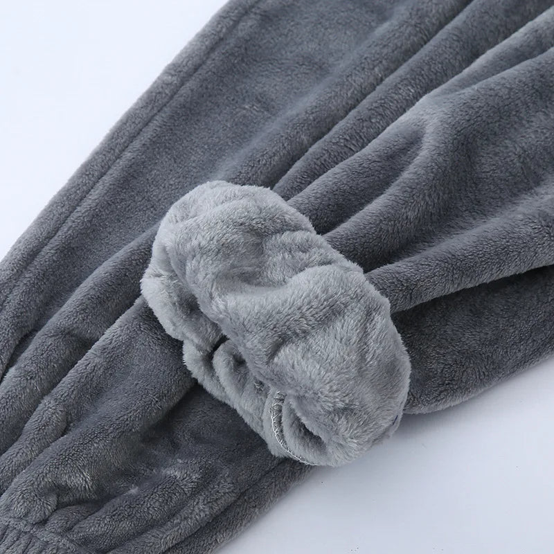 Gros plan sur le bas du pantalon d’un pyjama en flanelle pour homme, en tissu gris ultra doux et moelleux, avec revers épais et finition chaude. Matière confortable idéale pour l’hiver.