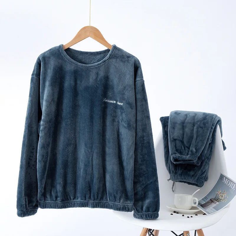 Pyjama en flanelle pour homme composé d’un haut à manches longues bleu gris suspendu sur cintre et d’un pantalon assorti posé sur une chaise. Ensemble chaud, doux et très confortable, idéal pour l’hiver et les moments de détente à la maison.