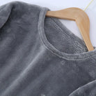 Gros plan sur le haut d’un pyjama en flanelle pour homme, en tissu gris doux et duveteux, suspendu sur un cintre. Matière chaude, moelleuse et très confortable, idéale pour l’hiver.