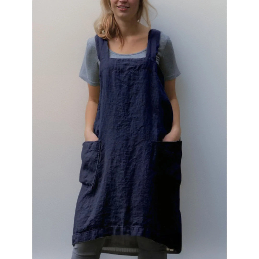 Tablier robe femme pratique et confortable, en lin bleu marine, coupe droite avec larges bretelles et grandes poches avant, porté sur un t-shirt gris.