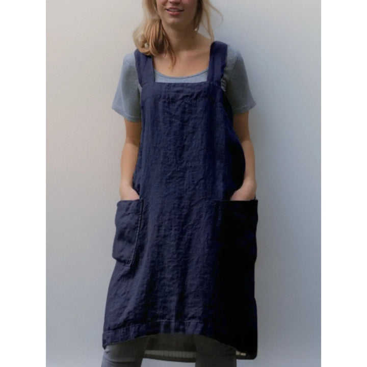Tablier robe femme pratique et confortable, en lin bleu marine, coupe droite avec larges bretelles et grandes poches avant, porté sur un t-shirt gris.