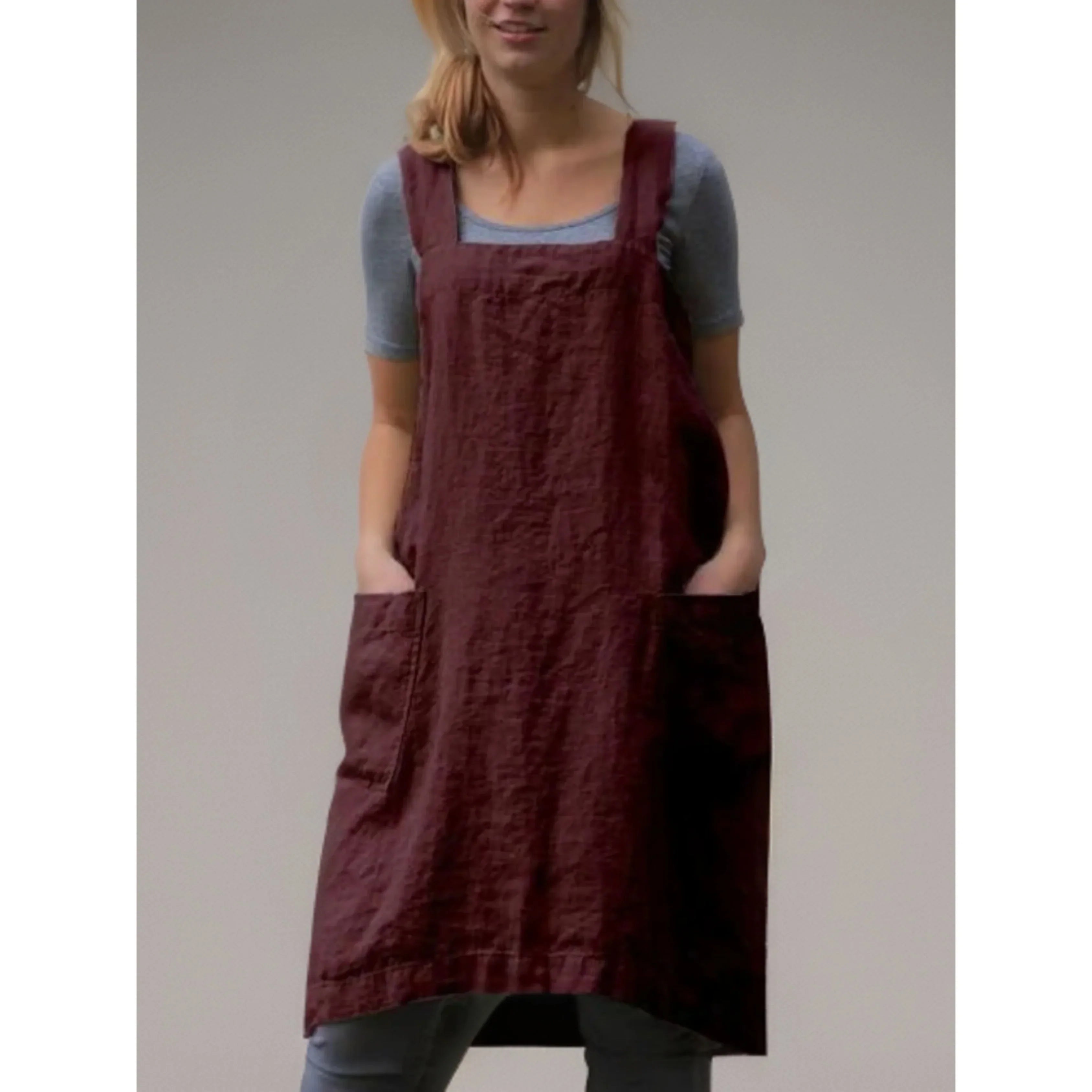 Tablier robe femme pratique et confortable, en lin bordeaux, coupe droite avec larges bretelles et grandes poches avant, porté sur un t-shirt gris.