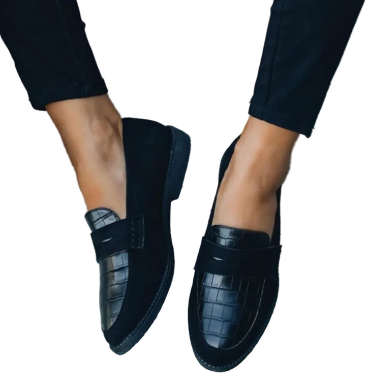 Mocassins femme élégants et confortables noirs, dessus effet croco et bandeau style penny loafer, portés avec pantalon noir, vue de dessus.