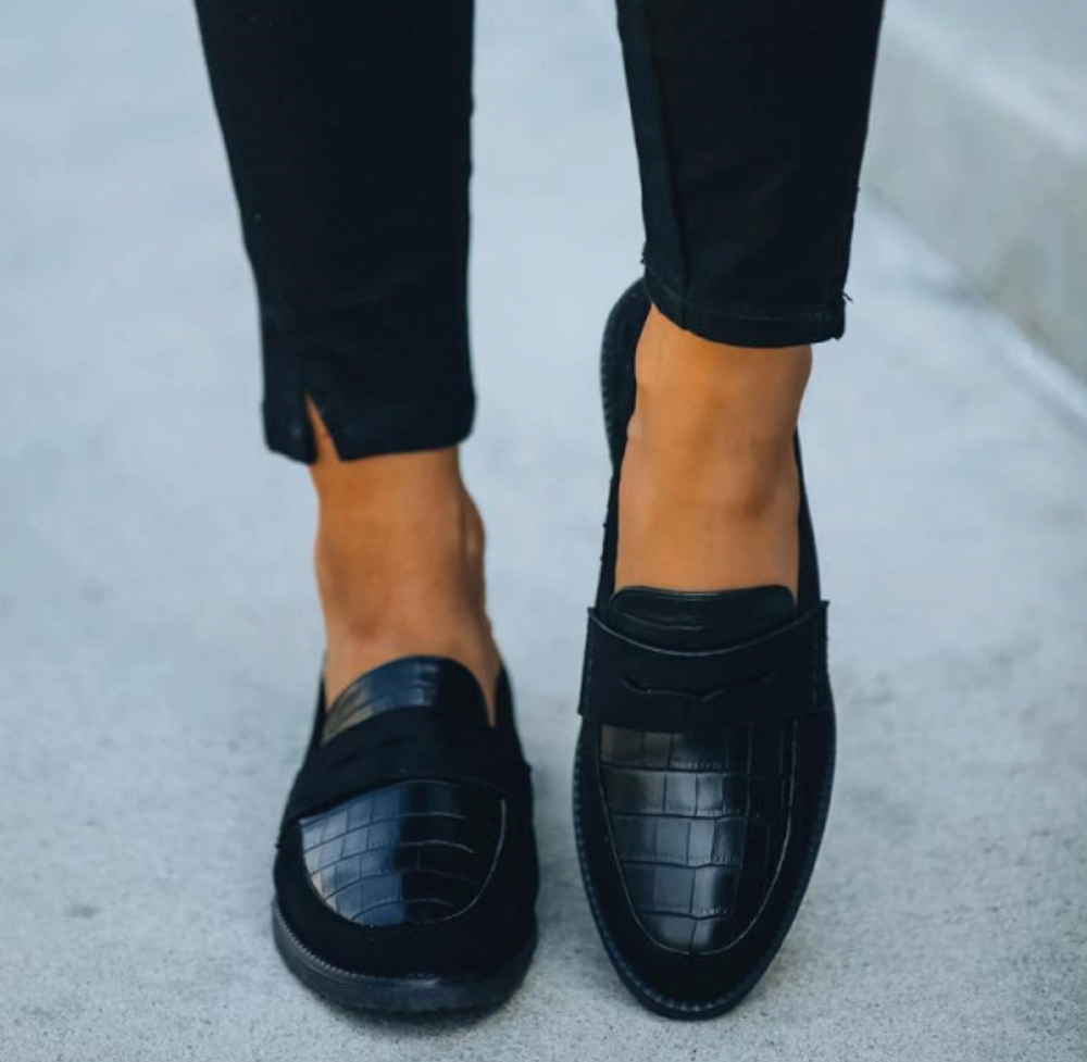 Mocassins femme élégants et confortables noirs, empiècement effet croco sur le dessus, portés avec pantalon noir, vue rapprochée.