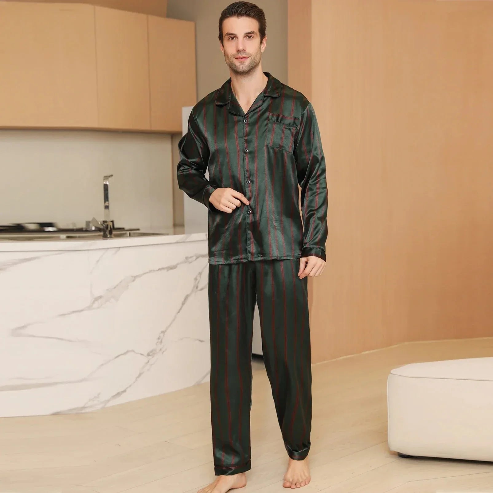 Homme marchant dans un intérieur moderne portant le pyjama satin pour homme Julien, ensemble léger et agréable composé d’une chemise à manches longues boutonnée et d’un pantalon assorti, en satin vert à fines rayures rouges, offrant une allure élégante et un confort optimal pour la nuit ou la détente à la maison.