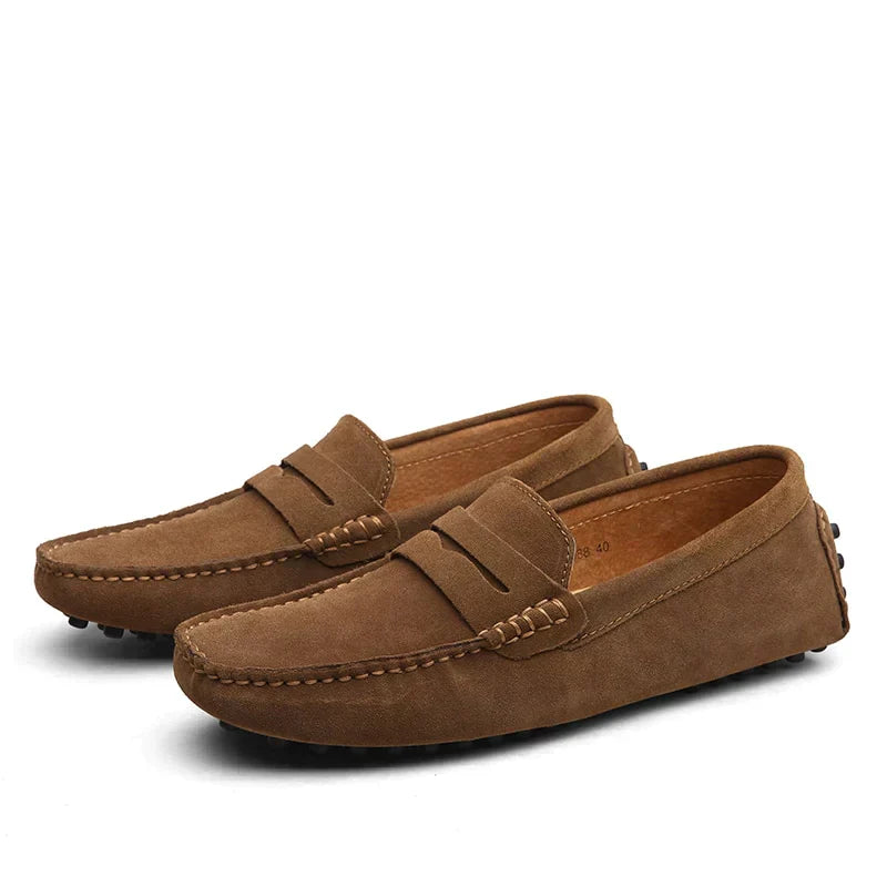 Une paire de mocassins en daim marron pour homme, avec des coutures délicates et une semelle à picots pour une meilleure adhérence et confort. Ces chaussures allient élégance et praticité pour un usage quotidien.