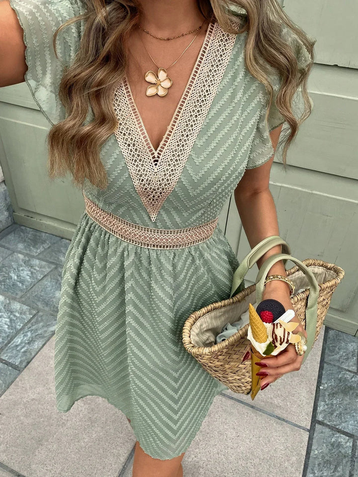 Détail de la robe mini d’été pour femme vert pastel, légère et confortable, avec décolleté en dentelle raffinée et taille cintrée, idéale pour un style estival élégant.
