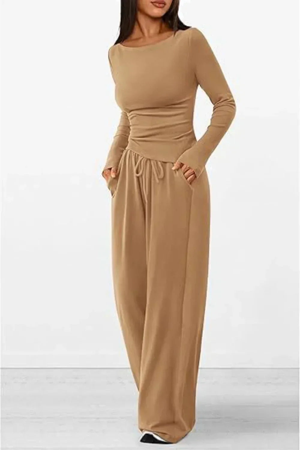 Femme portant un ensemble lounge beige composé d’un haut à manches longues moulant et d’un pantalon ample à taille élastique avec cordon. Tenue douce, confortable et élégante, parfaite pour les journées détente ou un look casual tendance.