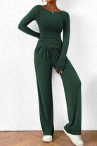 Femme portant un ensemble lounge vert foncé, composé d’un haut à manches longues moulant et d’un pantalon fluide à taille élastique avec cordon. Tenue douce, confortable et élégante, idéale pour le quotidien, les moments de détente ou un style décontracté tendance.