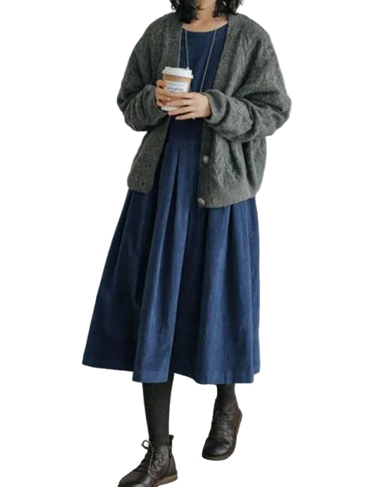 Robe femme élégante et raffinée, bleu marine, coupe midi évasée et fluide, portée avec un cardigan gris, collants foncés et bottines en cuir.