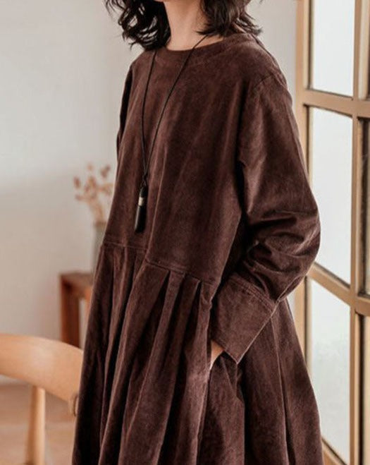 Gros plan de la robe femme élégante et raffinée, marron foncé, tissu texturé, manches longues, taille froncée avec plis et poches latérales.
