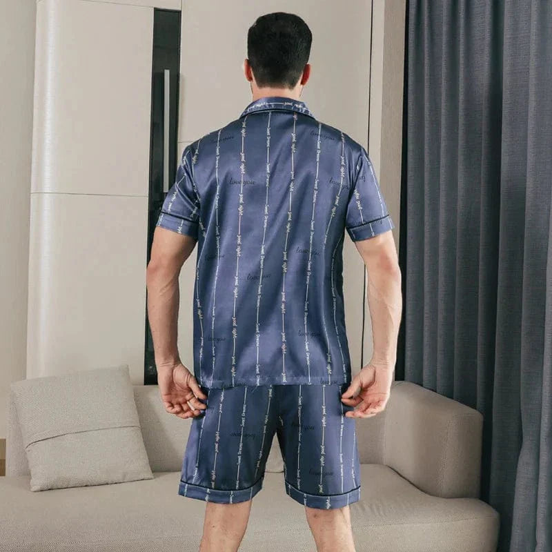 Vue arrière du shorty en satin pour homme, composé d'une chemise à manches courtes et d'un short assorti. Le tissu satiné, avec son éclat doux et soyeux, procure confort et légèreté. Le modèle porte le pyjama avec une pose décontractée, montrant la coupe élégante et moderne du produit. Idéal pour les moments de détente à la maison, alliant confort et style.