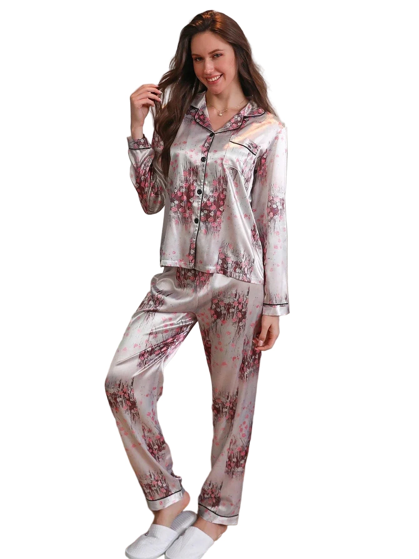 Femme souriante portant un pyjama long en satin gris perle à motifs floraux roses. Ensemble composé d’un haut boutonné à manches longues avec col passepoilé et d’un pantalon assorti. Pyjama doux, fluide et élégant, parfait pour allier confort et style à la maison.