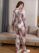 Vue de dos d’une femme portant un pyjama long en satin gris clair avec imprimés floraux roses. Ensemble composé d’un haut à manches longues et d’un pantalon assorti, au tombé fluide et à la finition brillante. Lingerie élégante et confortable, parfaite pour des soirées détente à la maison.