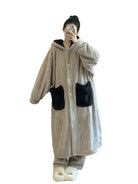 un peignoir long gris à capuche avec boutons, poches contrastées noires et tissu ultra-doux, idéal pour rester au chaud et à l’aise à la maison.