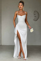 Robe de soirée Landry en satin blanc, avec des bretelles fines et un design fluide. La fente sur le côté ajoute une touche sexy et sophistiquée à ce modèle chic et élégant, parfait pour une soirée glamour.