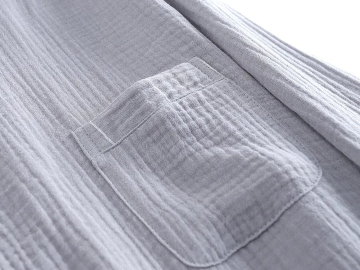 Gros plan sur la poche poitrine d’un haut de pyjama homme en tissu gris clair gaufré. Matière douce, légère et confortable, idéale pour la détente et les nuits paisibles.