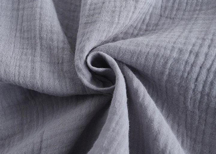 Gros plan sur le tissu gris clair gaufré du pyjama homme, montrant une matière douce, légère et respirante, idéale pour un confort optimal jour et nuit.