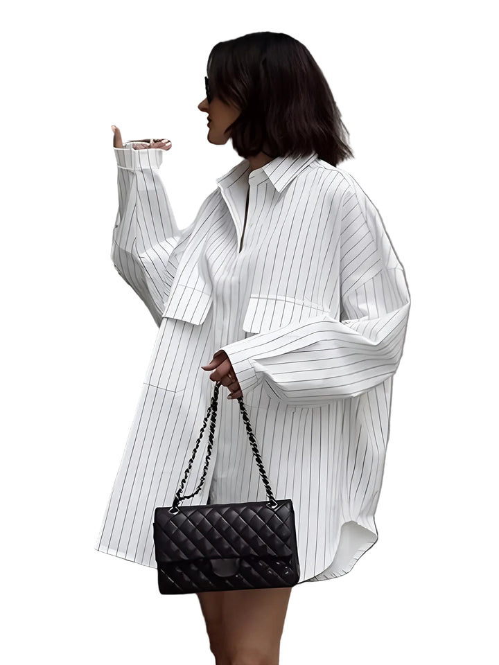 Robe-chemise Lexi pour femme, coupe ample et confortable, coloris blanc à rayures fines, manches longues et col classique, portée avec un sac noir pour un look tendance et élégant en ville.