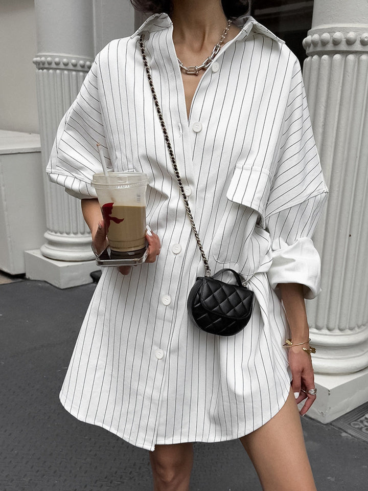 Robe-chemise Lexi pour femme, coupe ample et confortable, coloris blanc à fines rayures verticales, manches longues et col classique avec boutons, portée avec un petit sac noir pour un style tendance et décontracté.