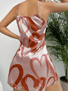 Femme portant la nuisette Lilou en satin rose clair, ornée de cœurs imprimés rose foncé. Coupe courte, fluide et élégante avec fines bretelles réglables. Tissu brillant et doux pour un confort optimal à la maison. Style féminin et raffiné, parfait pour une touche romantique et délicate.