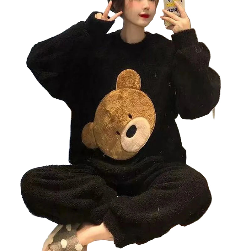 Femme portant un pyjama moelleux noir composé d’un haut à manches longues décoré d’une grande tête d’ours en relief et d’un pantalon assorti. Ensemble doux, chaud et relaxant, idéal pour le cocooning.
