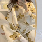 Femme portant un pyjama moelleux blanc cassé imprimé de petits oursons beiges. Ensemble composé d’un haut à manches longues et d’un pantalon assorti, idéal pour rester au chaud et se détendre confortablement à la maison.