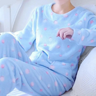 Femme portant un pyjama moelleux bleu pastel décoré de petits pois roses, composé d’un haut doux à manches longues et d’un pantalon assorti. Ensemble chaud, confortable et relaxant, parfait pour le cocooning à la maison.