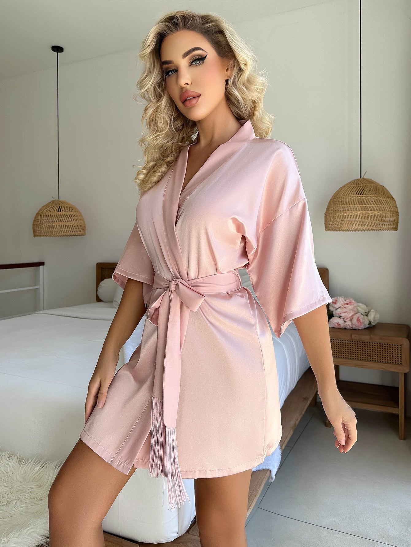 Cardigan pyjama femme Livie en satin rose poudré, coupe courte avec manches amples et ceinture à nouer, porté debout dans une chambre lumineuse.