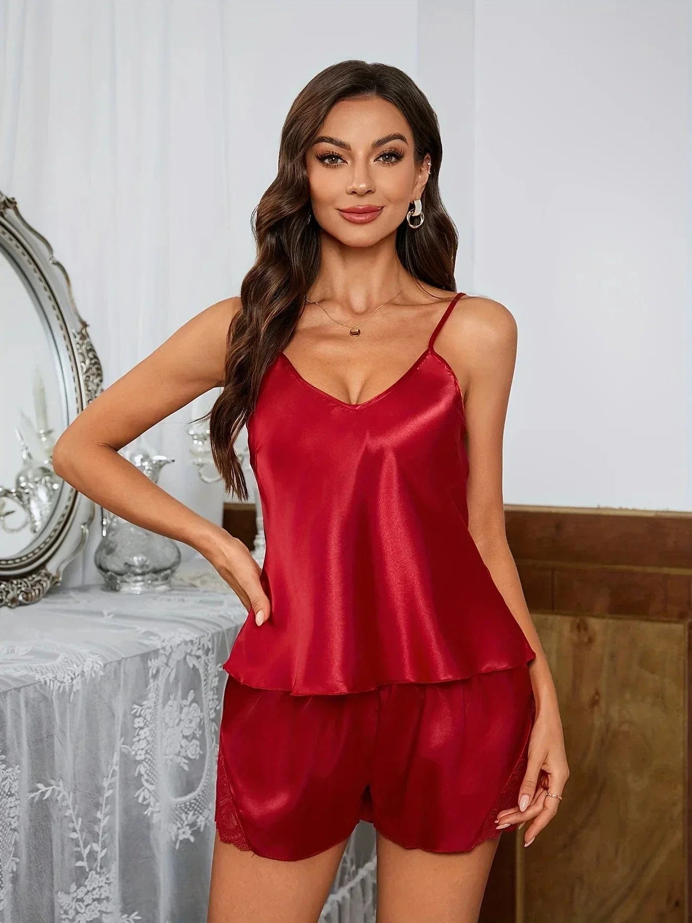 Femme portant un pyjama deux pièces en satin rouge bordeaux, composé d’un débardeur à fines bretelles et d’un short fluide avec détails en dentelle. Ensemble élégant, léger et confortable, parfait pour les nuits douces ou les moments de détente stylés à la maison.
