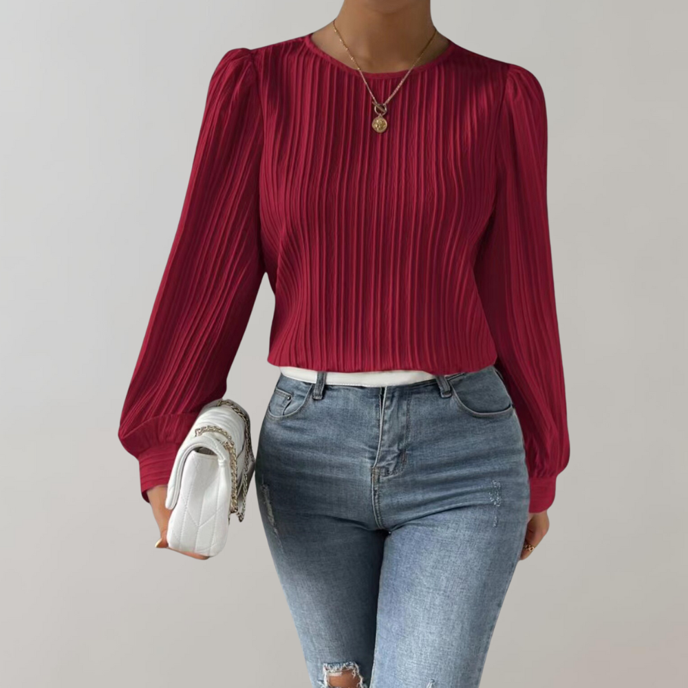 Top Lorna pour femme, élégant et confortable, coupe ajustée avec manches longues légèrement bouffantes, tissu plissé coloris rouge, porté avec un jean pour un look chic et moderne.
