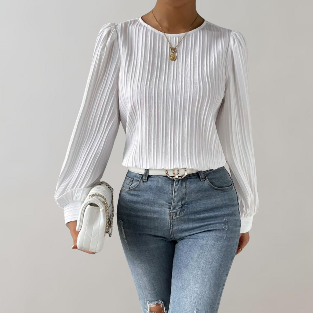 Top Lorna pour femme, élégant et confortable, coupe ajustée avec manches longues légèrement bouffantes, tissu plissé coloris blanc, porté avec un jean pour un look chic et moderne.
