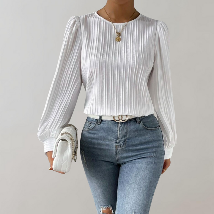 Top Lorna pour femme, élégant et confortable, coupe ajustée avec manches longues légèrement bouffantes, tissu plissé coloris blanc, porté avec un jean pour un look chic et moderne.