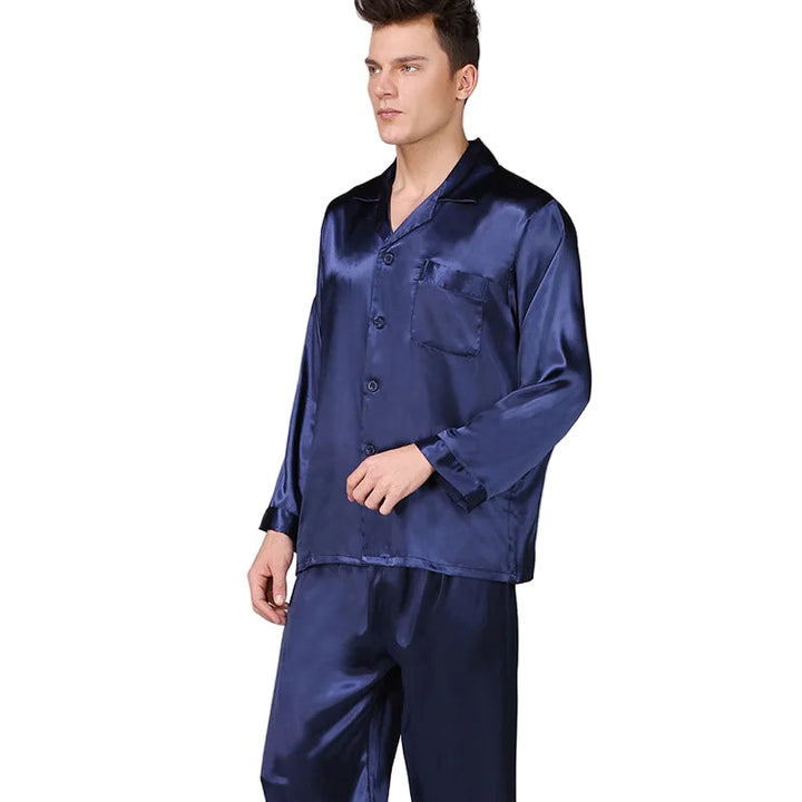 Homme portant un pyjama noir satiné composé d’une chemise à manches longues avec poche poitrine et d’un pantalon assorti. Ensemble doux, élégant et très confortable, idéal pour des nuits stylées et agréables.