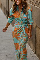 Robe portefeuille à imprimé floral turquoise et orange, avec une coupe flatteuse et un nœud à la taille, idéale pour une tenue chic et décontractée. Parfaite pour les journées d'été.