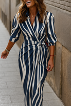 Robe portefeuille à rayures bleues et blanches, avec une coupe moderne et une taille cintrée par un nœud, idéale pour une tenue chic et décontractée. Parfaite pour un look élégant et frais.