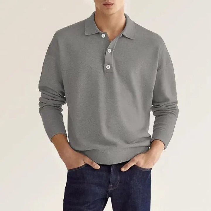 Ce polo gris pour homme, à manches longues, combine confort et élégance. Son design simple et soigné avec un col classique et des boutons contrastés en fait un choix parfait pour toutes les occasions, offrant à la fois un look décontracté et raffiné.