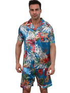 Shorty en satin pour homme, de style tropical avec un motif coloré de fleurs et de feuillage. Sur cette photo, un homme porte la chemise à manches courtes et le short assorti, parfait pour les journées estivales. Ce pyjama léger et doux est idéal pour la saison chaude, offrant confort et style.