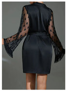 Vue de dos du peignoir Lucie en satin noir, avec manches longues transparentes décorées de cœurs et finitions à franges. Ceinture à nouer à la taille. Lingerie élégante et séduisante, idéale pour une touche glamour et féminine à la maison.