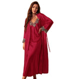 Femme portant une nuisette longue bordeaux avec un peignoir assorti. La nuisette présente un décolleté en V orné de dentelle florale contrastante, également présente aux manches du peignoir. Ensemble élégant, fluide et séduisant, idéal pour les soirées romantiques ou les instants de détente raffinés.
