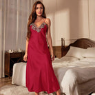 Femme debout dans une chambre, vêtue d’une nuisette longue en satin bordeaux avec fines bretelles et décolleté en V orné de dentelle grise florale. Lingerie élégante, fluide et séduisante, parfaite pour les soirées romantiques ou les moments de détente raffinés.