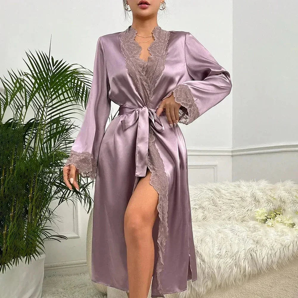pour femme en satin mauve brillant, doté de manches longues et bordé de dentelle délicate sur les poignets et l'encolure. Fermeture par ceinture nouée à la taille. Un modèle élégant et confortable, parfait pour une allure raffinée à la maison.