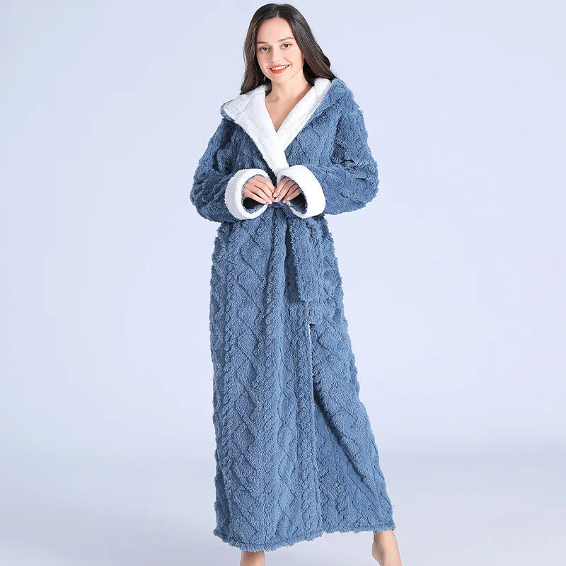 Femme portant le peignoir Maïa chaud et confortable, modèle bleu avec texture douce et doublure blanche, noué à la taille, posant debout en souriant.