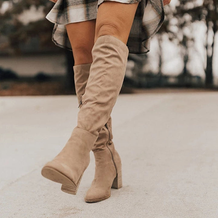 Bottines hautes en daim beige avec un talon carré, une fermeture éclair latérale, parfaites pour un look chic et tendance tout en offrant un confort optimal.