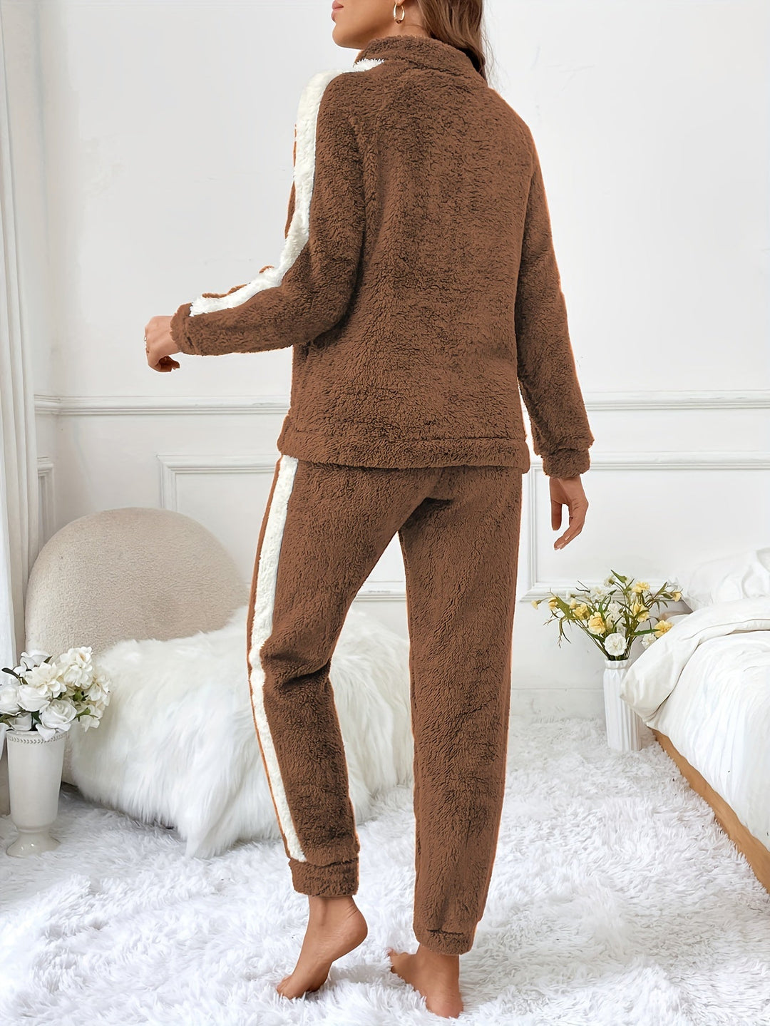 Vue arrière d’une femme portant un pyjama en polaire marron ultra doux, orné de bandes blanches sur les manches et les côtés du pantalon, parfait pour rester au chaud et confortable à la maison.