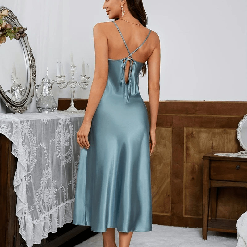 Vue arrière de la robe en satin bleu, avec des bretelles croisées et un détail de lien au dos pour un ajustement personnalisé. Sa coupe fluide et son tissu satinée créent une allure élégante et séduisante, idéale pour des occasions spéciales ou des soirées raffinées.