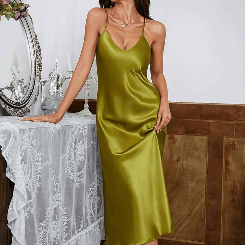 Robe en satin vert émeraude, avec un décolleté en V et des bretelles fines, offrant une allure élégante et raffinée. La coupe fluide et la texture satinée de la robe créent une silhouette séduisante, parfaite pour des occasions spéciales ou des moments glamour.