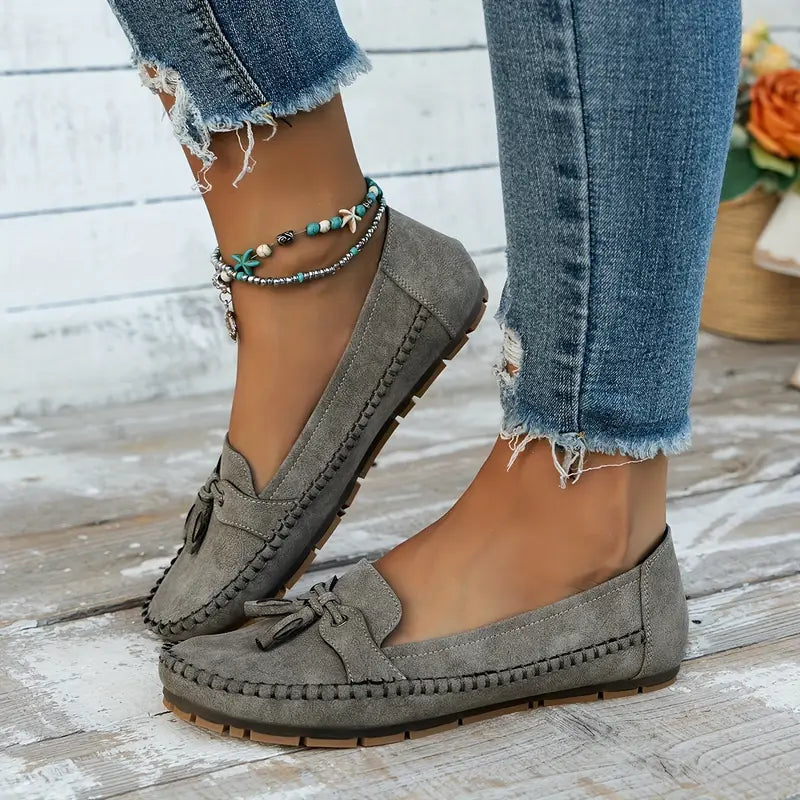 Mocassins gris élégants avec un petit nœud décoratif, parfaitement associés à un style décontracté et chic. Légers et confortables, ils sont idéaux pour un look estival. Les détails de couture raffinés et la semelle robuste offrent un confort optimal, tandis que les accessoires ajoutent une touche personnelle à la tenue. Parfaits pour compléter vos tenues quotidiennes.