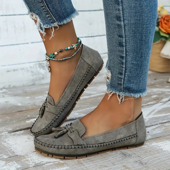 Mocassins gris élégants avec un petit nœud décoratif, parfaitement associés à un style décontracté et chic. Légers et confortables, ils sont idéaux pour un look estival. Les détails de couture raffinés et la semelle robuste offrent un confort optimal, tandis que les accessoires ajoutent une touche personnelle à la tenue. Parfaits pour compléter vos tenues quotidiennes.